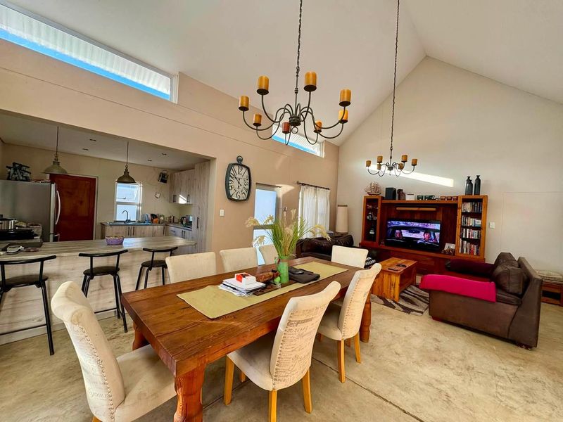 Spacious open-plan living and dining area featuring vaulted ceilings, clerestory windows, and a functional kitchen with a breakfast island.