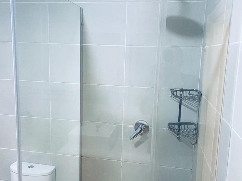 A functional bathroom featuring a glass-enclosed shower with modern fixtures and tiled wall finishes.