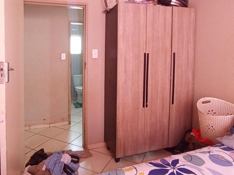 Bedroom featuring tiled flooring and direct access to an en-suite bathroom, showing signs of wear on the lower wall sections.