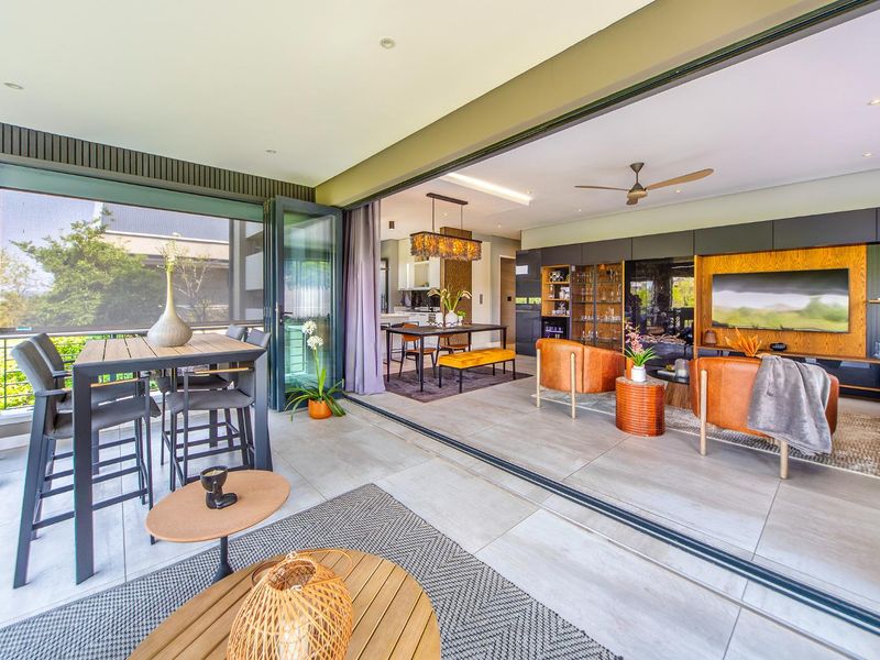 Spacious open-plan living area featuring large format floor tiles, recessed lighting, and seamless indoor-outdoor flow through expansive sliding glass doors.