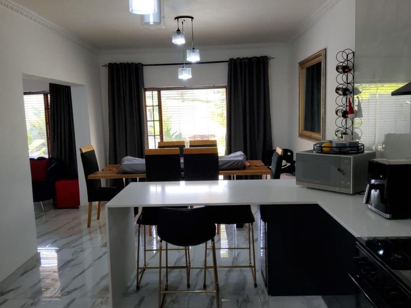 Open-plan living and dining area featuring modern marble-look flooring, a sleek kitchen island with quartz countertops, and contemporary pendant lighting.