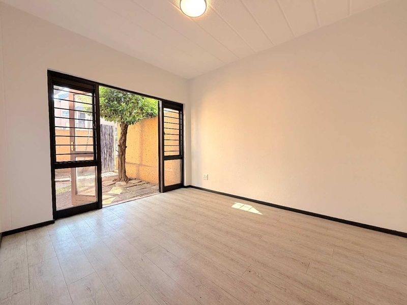 Bright and spacious living area featuring light-toned laminate flooring and a large sliding door providing direct access to the outdoor space.