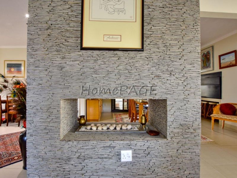 A central feature wall finished in stacked stone with a built-in gas fireplace, serving as a focal point between living and dining areas.