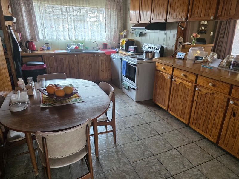 A functional kitchen featuring timber cabinetry, tiled flooring, and a freestanding oven, offering a traditional layout with ample storage space.