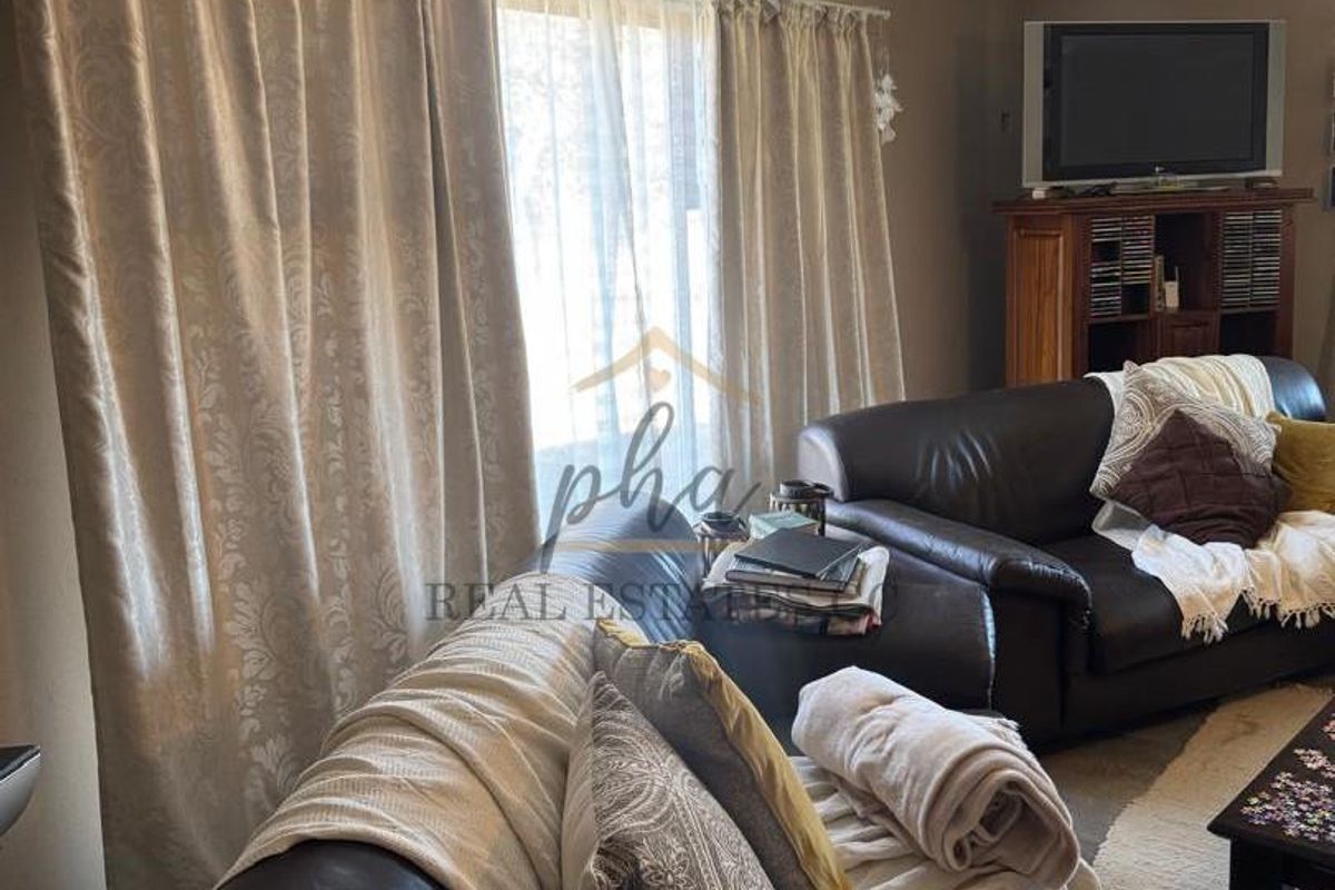 A comfortable living room area featuring large windows with curtains, providing a functional space for relaxation.