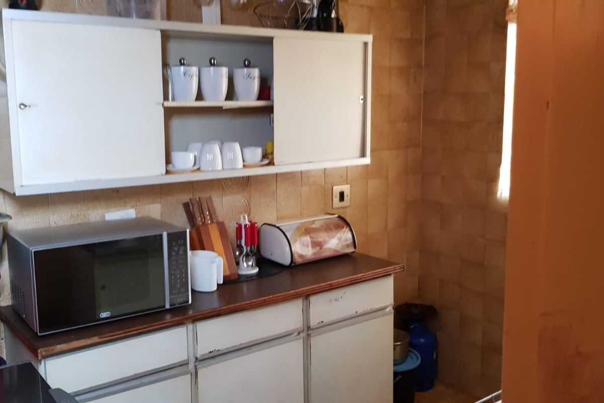 A compact kitchen area featuring dated cabinetry and tiled wall finishes, offering potential for a modern renovation.