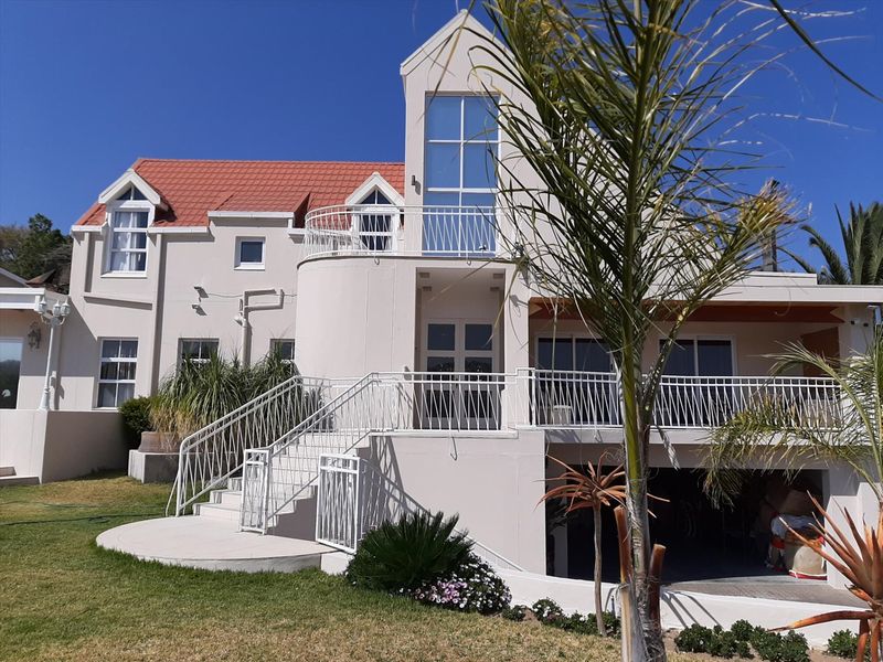 Rear elevation of a multi-story house featuring a terracotta tiled roof, upper-level balcony with metal railings, and an external staircase leading to the garden.