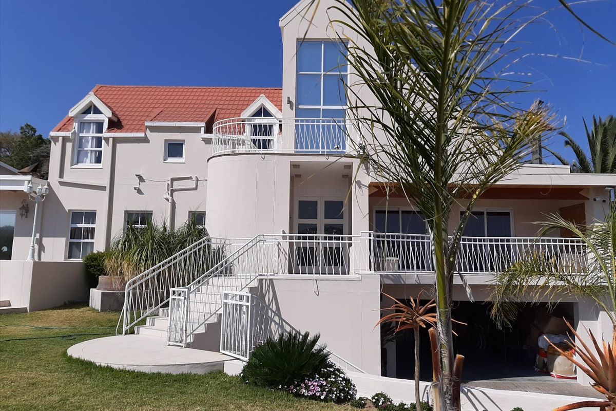 Rear elevation of a multi-story house featuring a terracotta tiled roof, upper-level balcony with metal railings, and an external staircase leading to the garden.