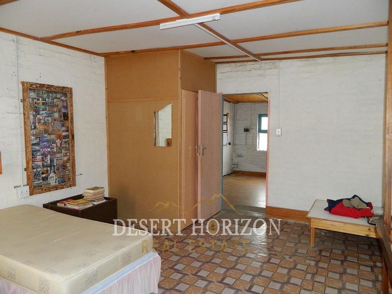 A bedroom featuring tiled flooring, exposed ceiling beams, and a built-in cupboard, requiring cosmetic updates to modernize the space.