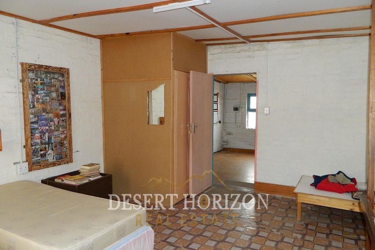 A bedroom featuring tiled flooring, exposed ceiling beams, and a built-in cupboard, requiring cosmetic updates to modernize the space.