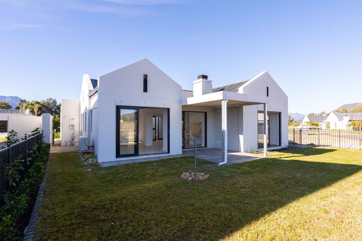 Rear view of a modern house featuring a covered patio, sliding glass doors, and a well-maintained garden area.