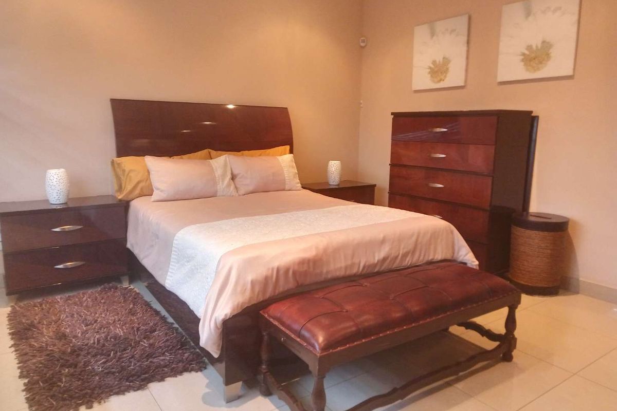 A well-maintained bedroom featuring neutral wall tones and tiled flooring, providing a comfortable and functional sleeping space.