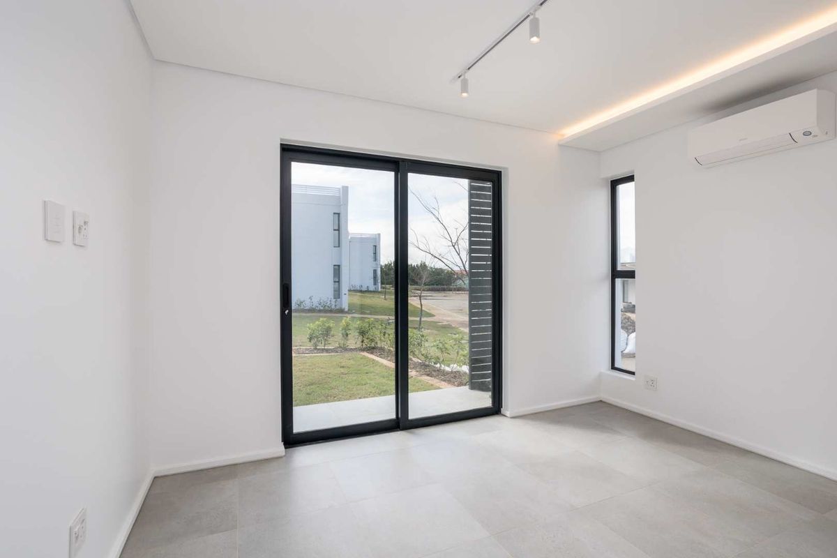 A bright, modern, and empty bedroom featuring tiled floors, a split-system air conditioner, and a sliding glass door leading to an outdoor area.