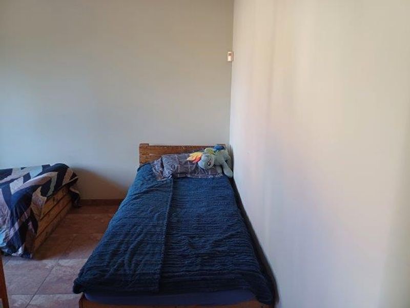 A simple bedroom featuring tiled flooring and neutral wall finishes, providing a functional space for rest.