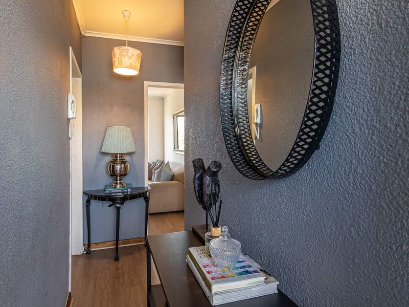 A functional hallway featuring laminate flooring, an intercom system, and neutral wall finishes, providing access to adjacent living areas.