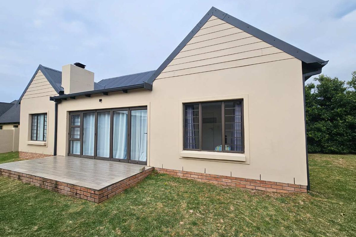 Rear view of the house featuring a tiled patio, sliding glass doors, and a brick-based exterior wall with a chimney.