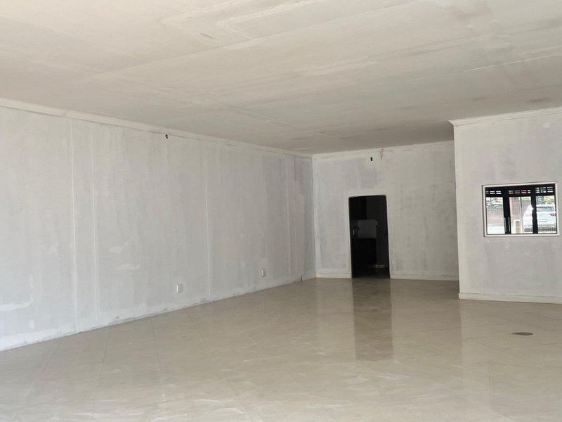 A spacious, empty open-plan retail area featuring tiled flooring and unfinished wall surfaces, ready for custom fit-out and final painting.