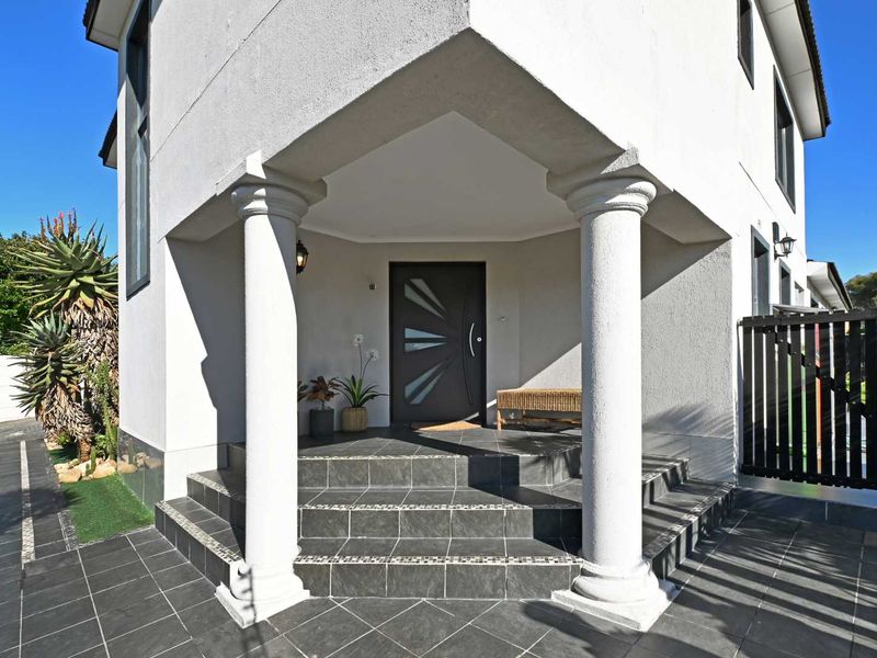 A well-maintained front entrance featuring tiled steps, decorative columns, and a modern front door, providing a welcoming and secure entry to the home.