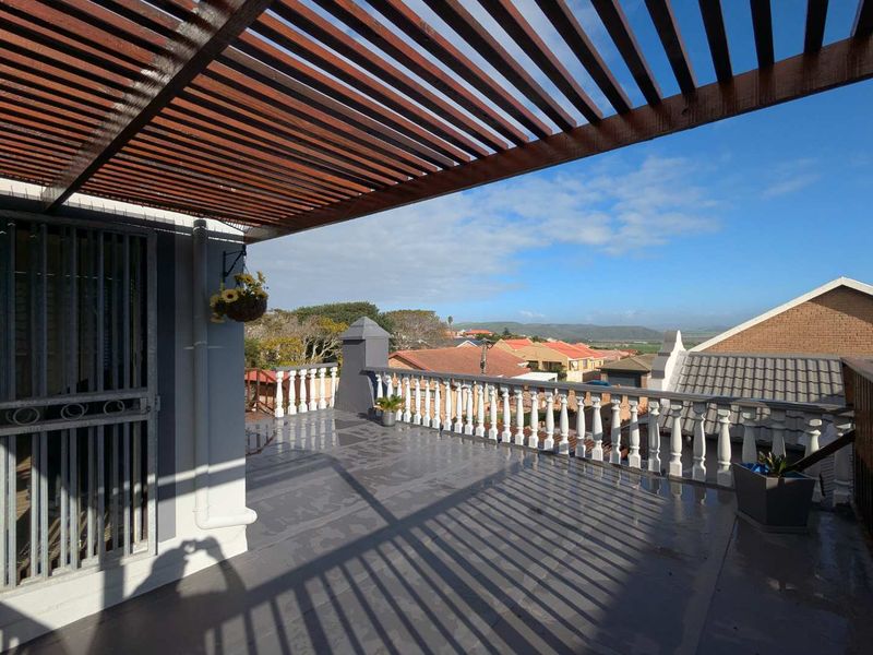 An elevated balcony featuring a timber pergola, classic balustrade railing, and expansive views of the surrounding neighborhood.