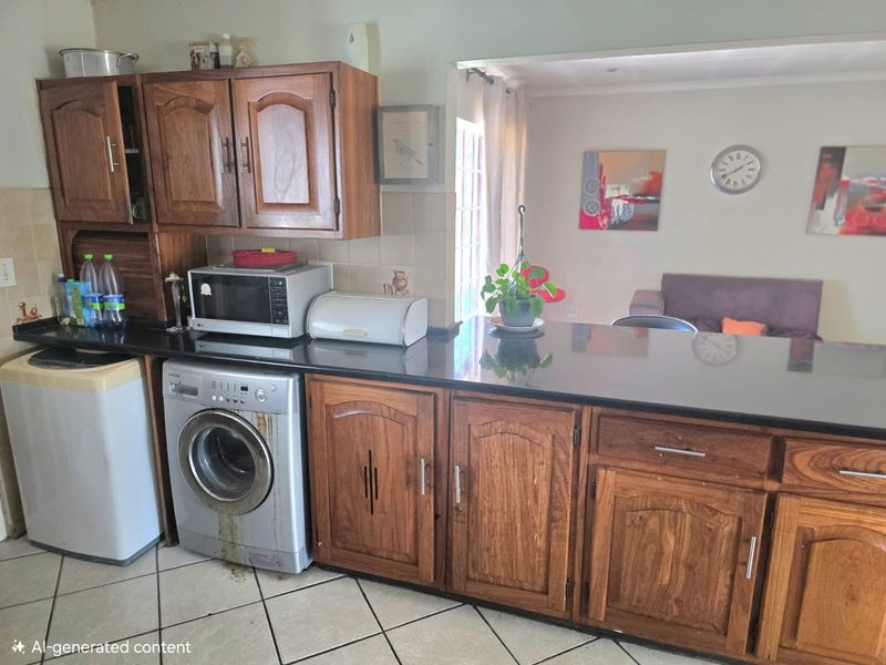 Open plan kitchen area featuring wooden cabinetry, granite countertops, and a breakfast bar, seamlessly connecting to the adjacent living space.