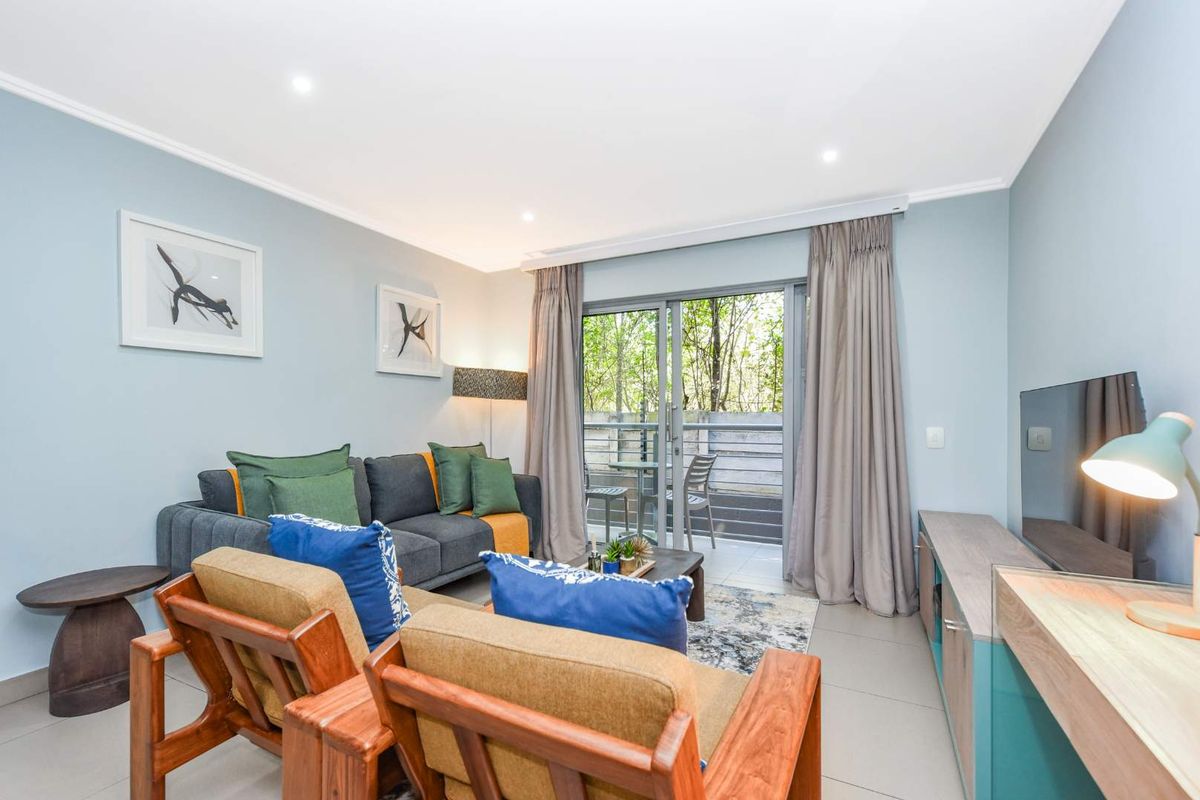 A well-lit living room featuring tiled flooring, recessed downlights, and a sliding glass door providing access to an outdoor balcony area.