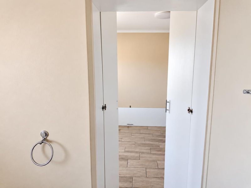 A view through a doorway into an empty room featuring wood-look tiled flooring and neutral wall finishes.