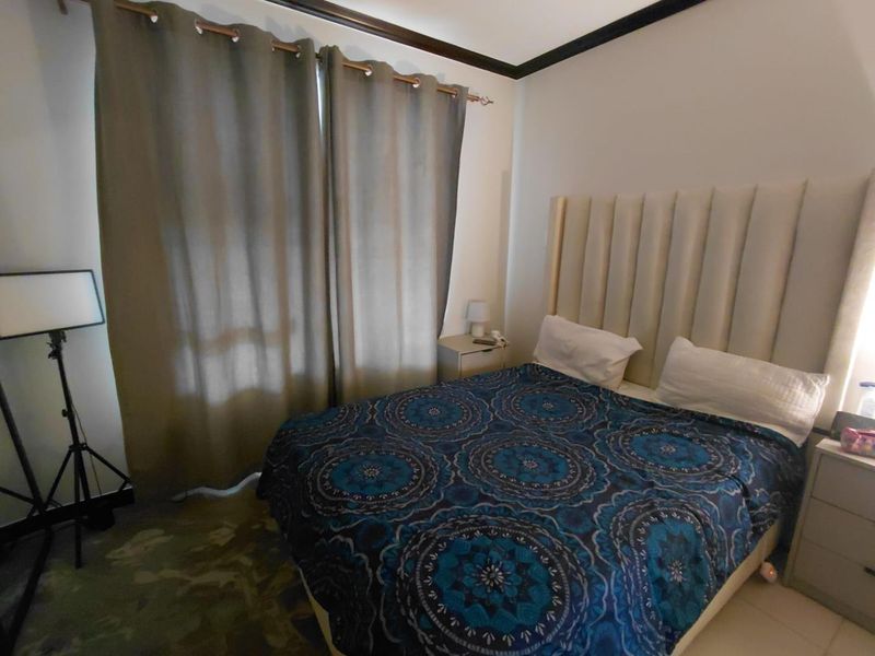A bedroom featuring neutral walls, crown molding, and floor-to-ceiling curtains, providing a functional space with potential for modern aesthetic updates.