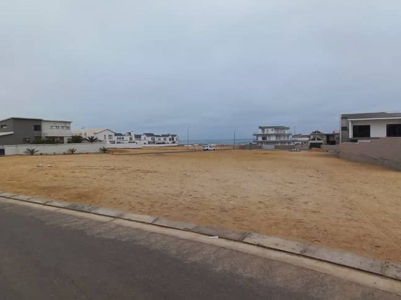 A vacant residential plot situated in a coastal neighborhood, featuring street access and boundary walls, offering potential for new construction.