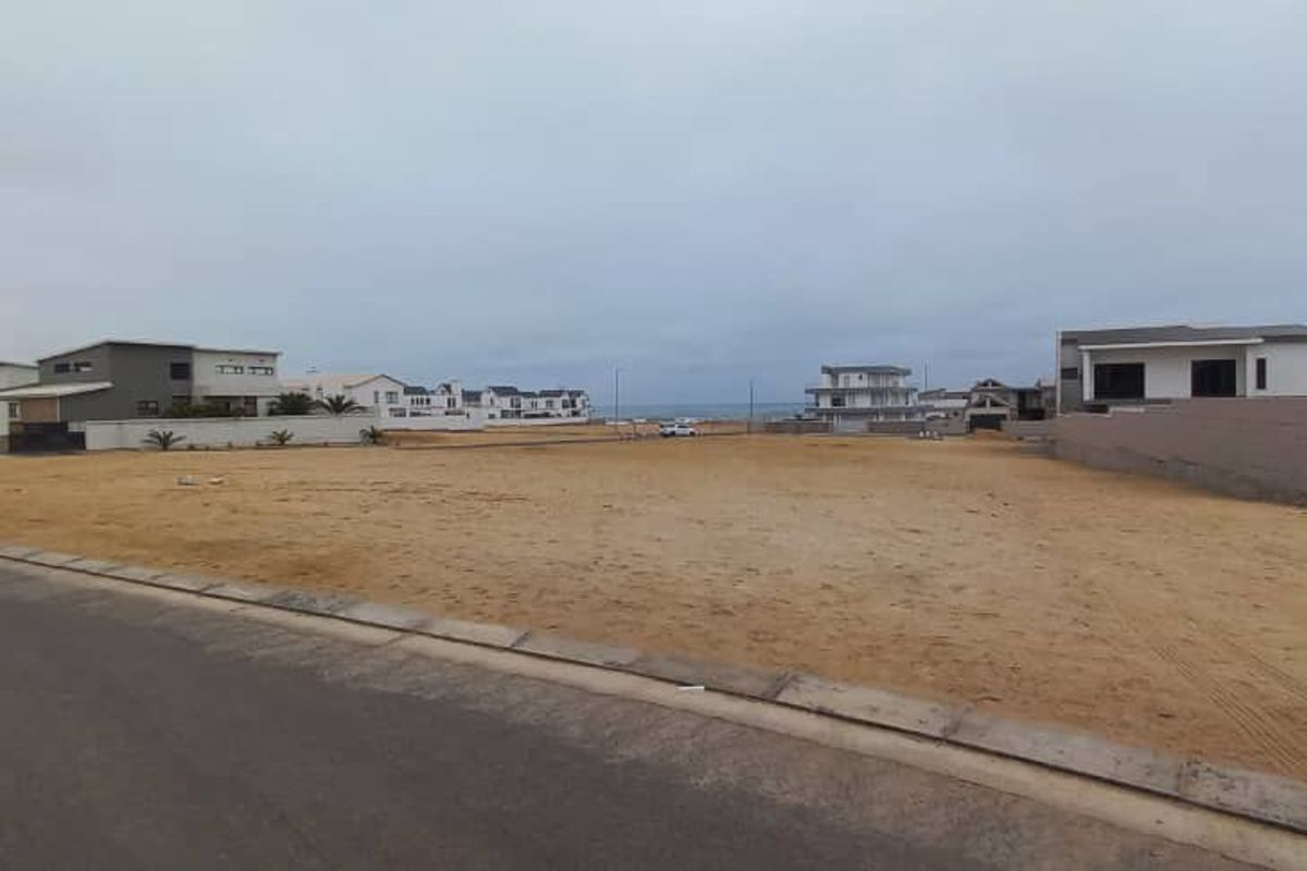 A vacant residential plot situated in a coastal neighborhood, featuring street access and boundary walls, offering potential for new construction.