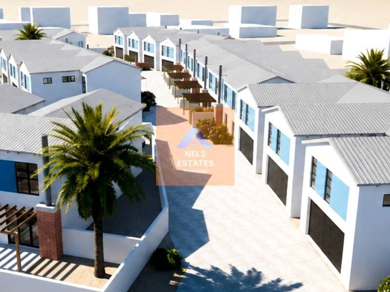 Aerial view of a modern townhouse development featuring uniform pitched roofs, paved driveways, and coastal proximity.
