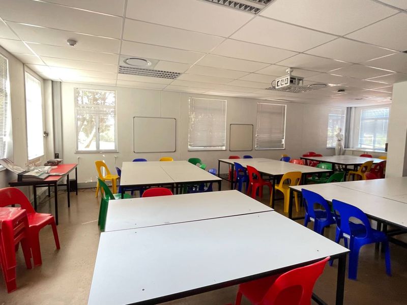 A functional office or training room featuring a suspended ceiling, recessed lighting, integrated projector, and multiple whiteboards, suitable for collaborative work or educational purposes.