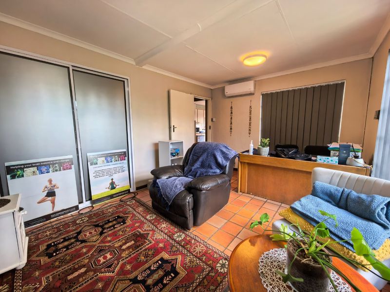 A functional office space featuring terracotta floor tiles, built-in sliding door cupboards, and a wall-mounted split-system air conditioner.
