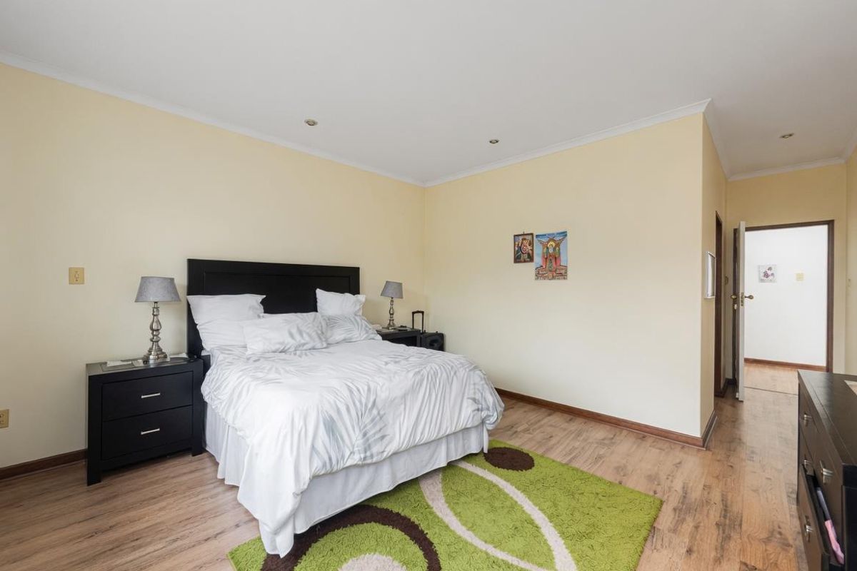 A spacious bedroom featuring laminate flooring, recessed downlighting, and neutral wall finishes, providing a comfortable and functional living space.
