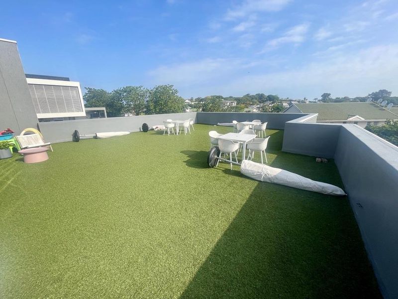 Spacious rooftop terrace featuring artificial turf flooring and perimeter parapet walls, offering an open-air outdoor entertainment area.