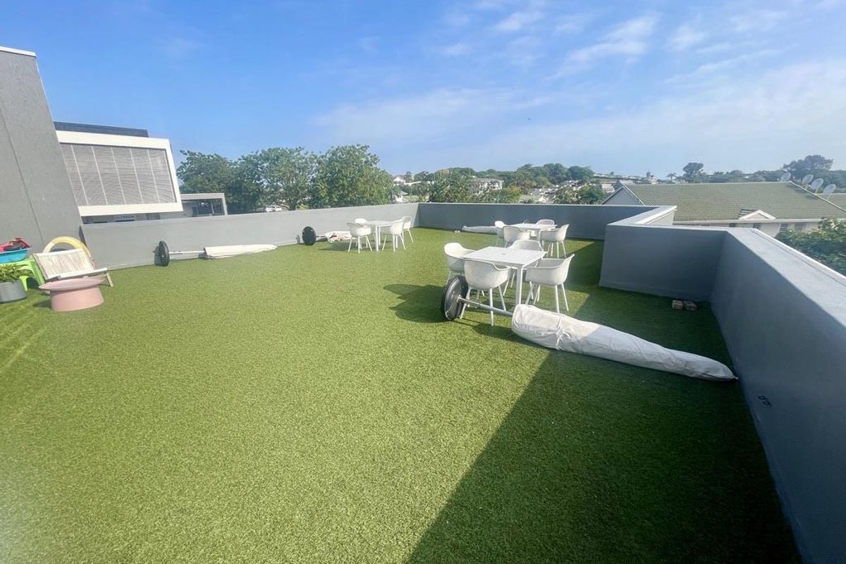 Spacious rooftop terrace featuring artificial turf flooring and perimeter parapet walls, offering an open-air outdoor entertainment area.