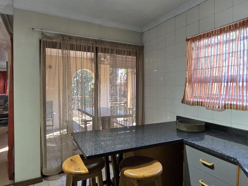Open plan kitchen area featuring granite countertops, built-in cabinetry, and a sliding door providing access to the outdoor patio space.