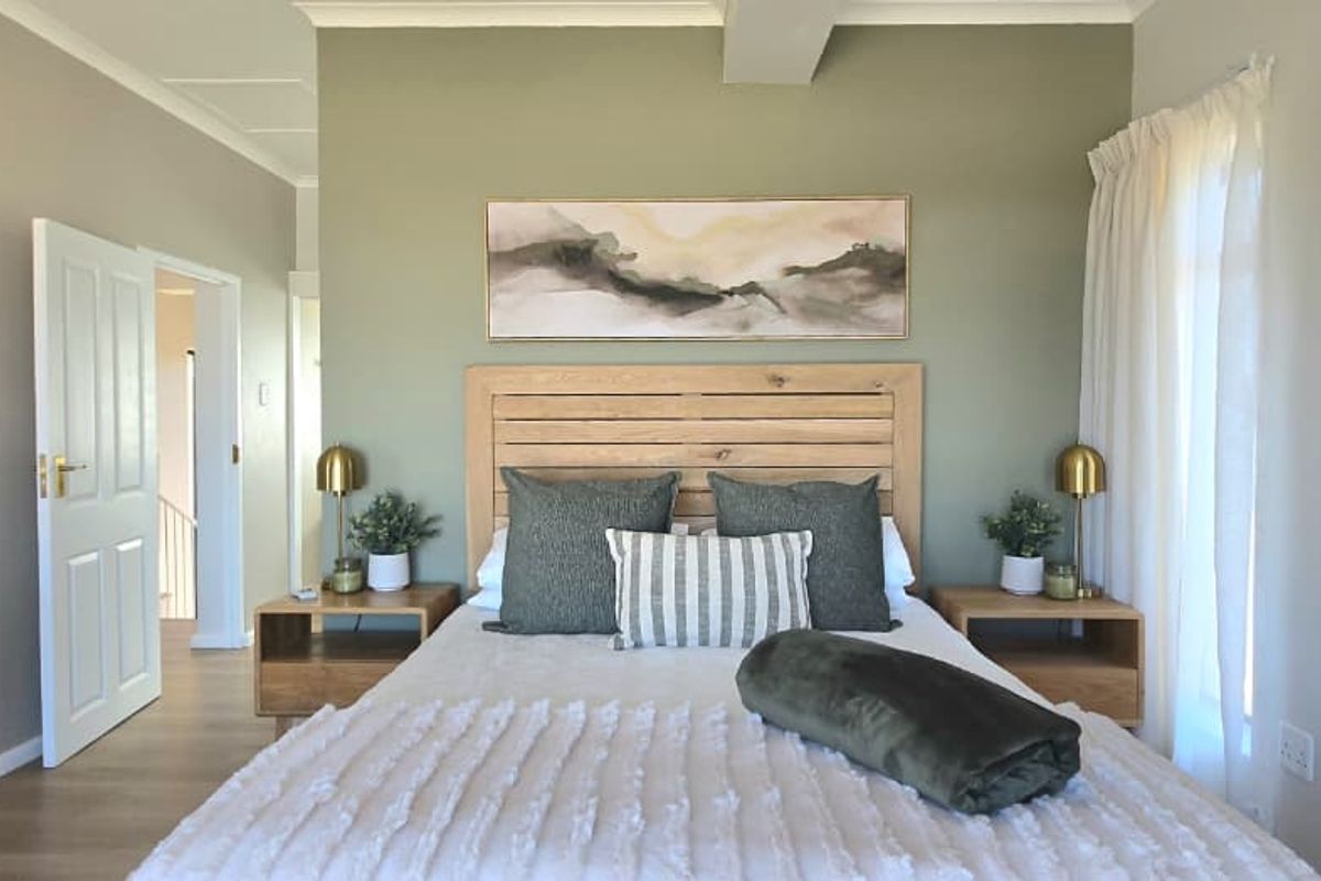 A well-maintained bedroom featuring neutral wall tones, wood-look flooring, and a central accent wall.