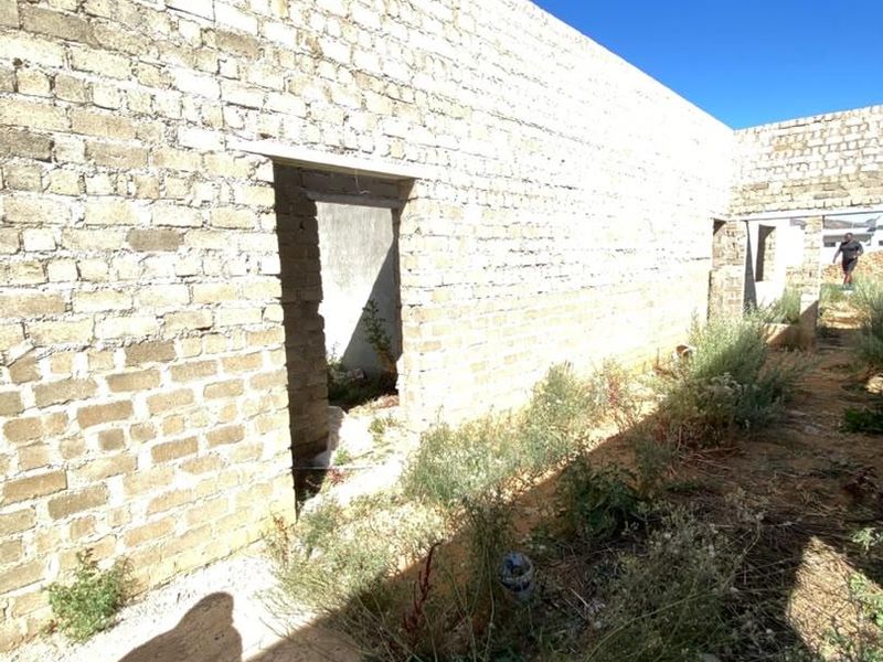 An unfinished exterior view of a property under construction, featuring exposed brick walls and open doorways in a shell state.