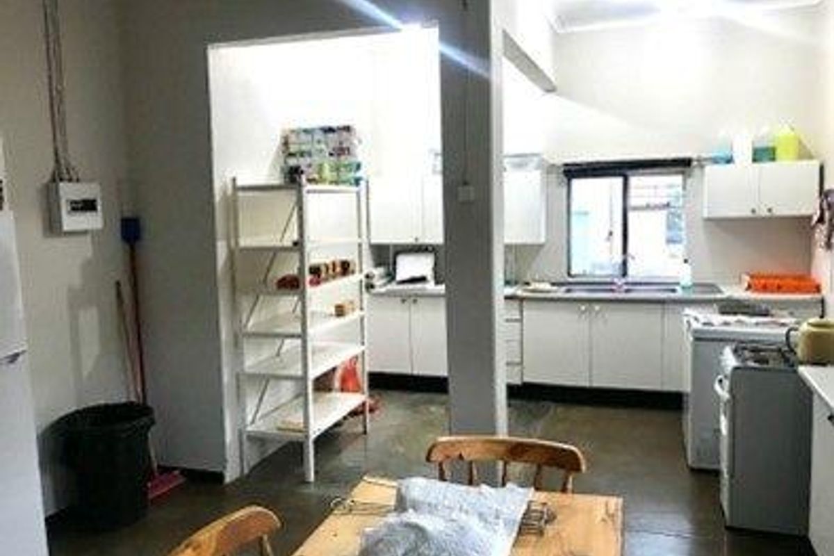 A functional kitchen and scullery area featuring white cabinetry, a double sink, and tiled flooring, providing ample space for food preparation and storage.