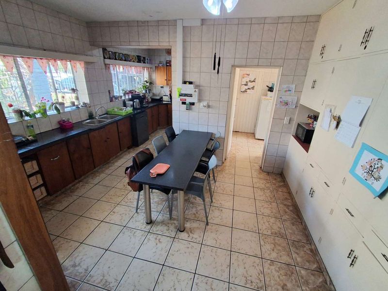 A functional kitchen featuring tiled walls and flooring, extensive built-in cabinetry, and a double bowl sink, offering potential for a modern renovation.