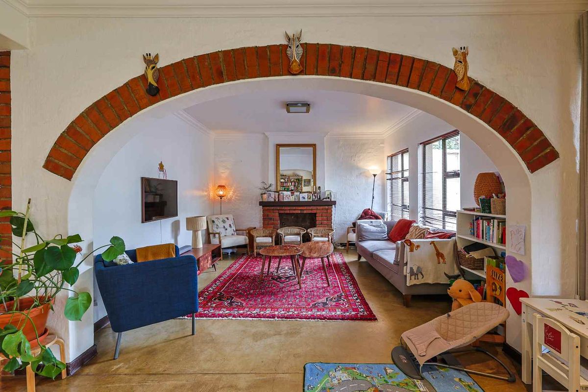 A spacious living room featuring a prominent brick archway, a built-in brick fireplace, and polished concrete flooring.