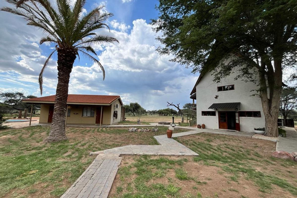 Exterior view of the farm property featuring a main dwelling and a secondary building connected by a paved stone walkway in a rural setting.