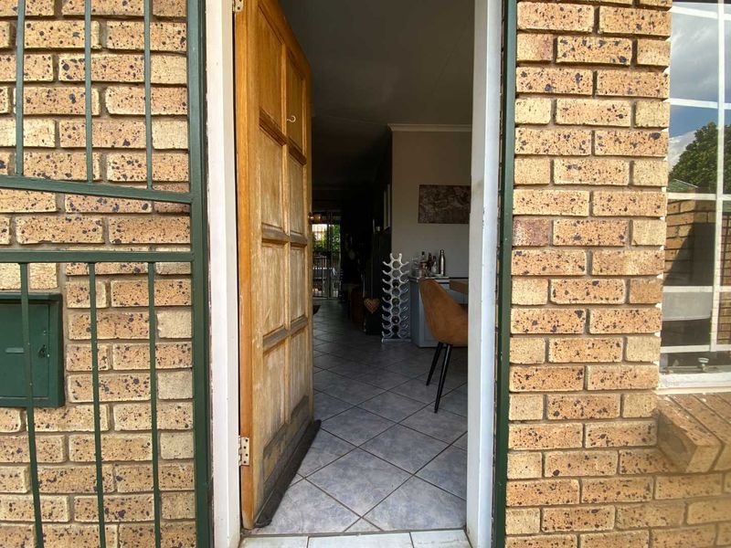 View through the front entrance door showing the tiled interior living space and face brick exterior facade.