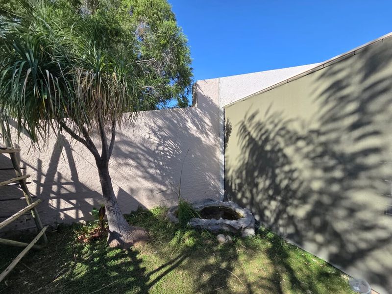 A small private garden area featuring a stone water feature and high boundary walls.