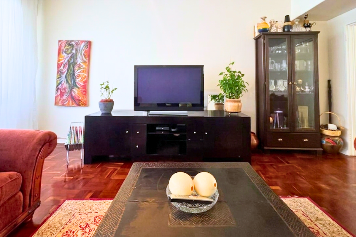 A comfortable living room featuring warm-toned parquet flooring and a neutral wall palette, providing a classic foundation for interior design.