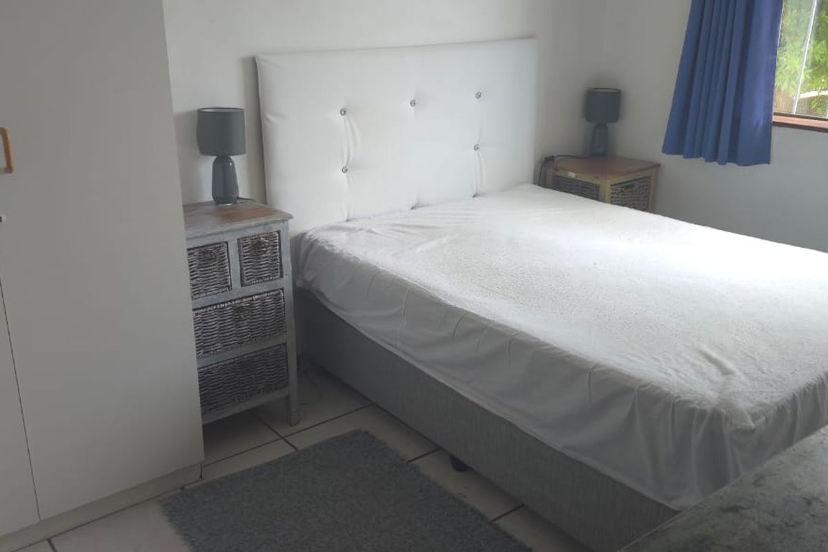 A functional bedroom featuring tiled flooring, a built-in wardrobe, and a window fitted with security bars.