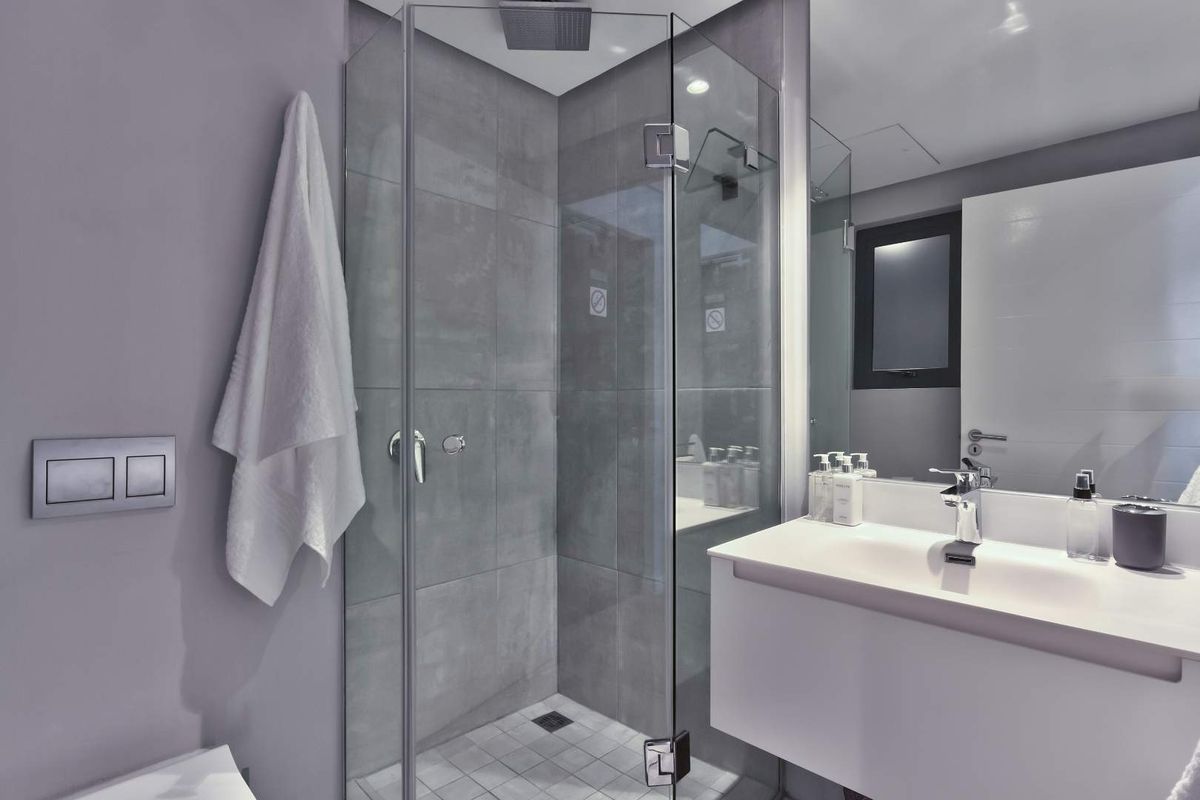Modern bathroom featuring a glass-enclosed shower with a rain shower head, a floating vanity with an integrated basin, and a large wall mirror.