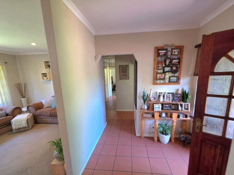 Welcoming entrance hall featuring terracotta-style floor tiles and a solid timber front door, providing direct access to the adjacent living area and hallway.