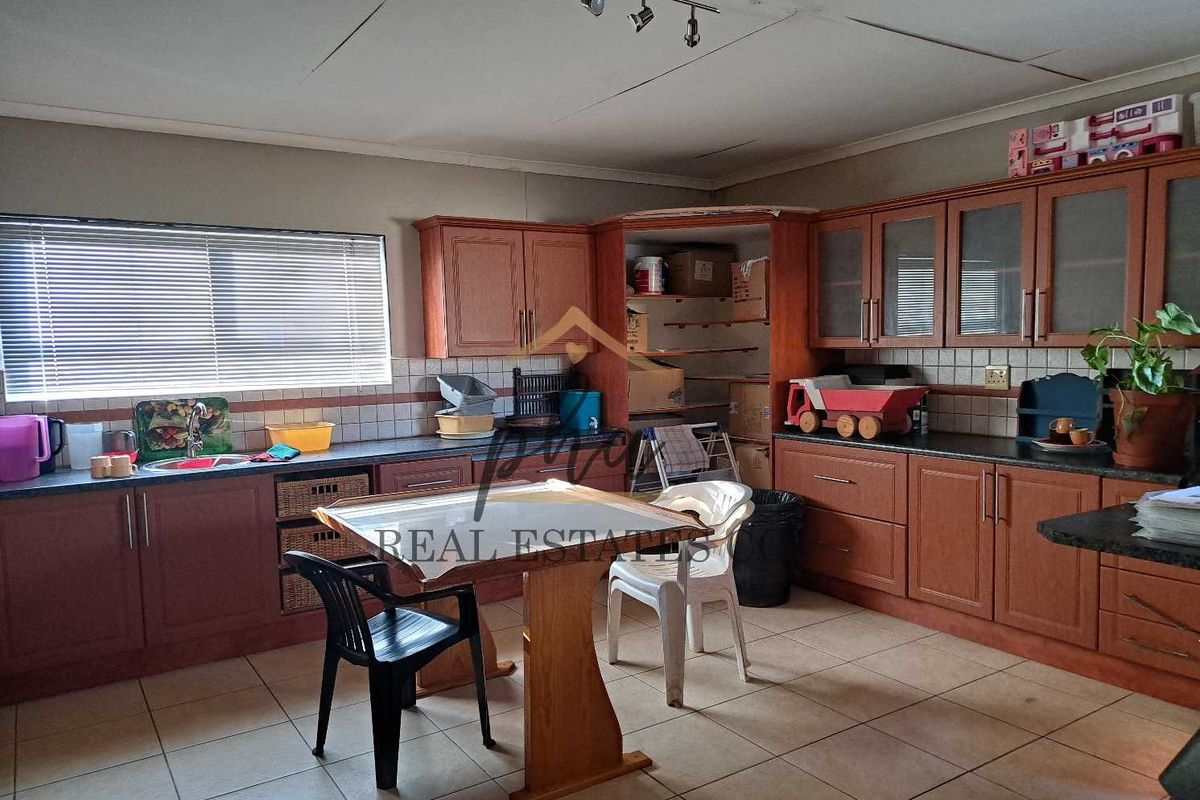 A dated kitchen featuring wood-tone cabinetry, tiled backsplash, and tiled flooring, offering a functional layout with potential for modern updates.