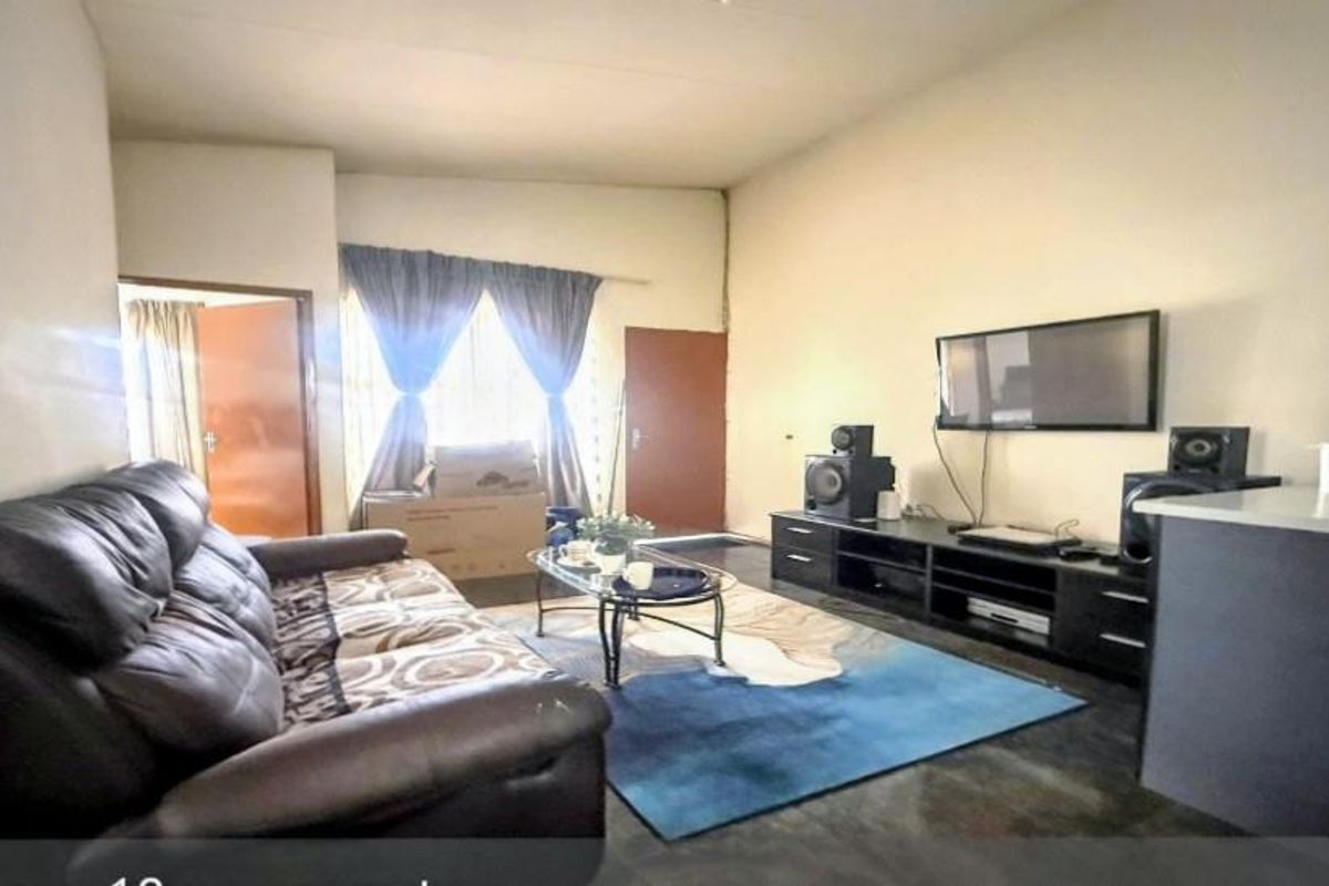 A spacious living room featuring neutral walls, tiled flooring, and a functional layout with direct access to adjacent areas.